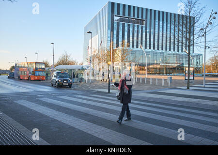 Femme sur le passage pour piétons entre la municipalité et la Société de construction de Cube street Shopping Centre à Corby, Northants, England. Banque D'Images