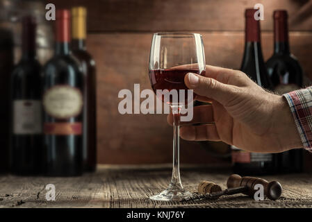 L'expérience de dégustation de vin dans la cave rustique et un bar à vin : sommelier tenant un verre de vin rouge délicieux et d'excellents vins collection sur th Banque D'Images