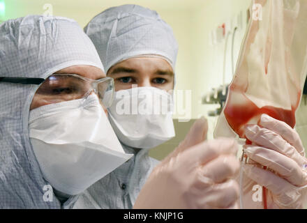 L'assistant technique pharmaceutique et biologique la Nemetz Michael Technicien de laboratoire Simon Kuebler (R) travaillent sur une nouvelle forme de thérapie cellulaire personnalisée contre le cancer avec la technologie hautement spécialisés à l'intérieur d'une chambre propre à l'Institut Fraunhofer pour la thérapie cellulaire et l'immunologie (IZI) à Leipzig, Allemagne, 20 novembre 2017. L'institut Fraunhofer travaille sur le projet conjoint avec le Novartis Pharma AG, afin de pouvoir élaborer la nouvelle forme de thérapie, la thérapie récepteur antigénique chimérique (panier). Il exige la reprogrammation de l'patients· propres cellules immunitaires pour traiter leur Banque D'Images