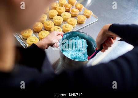 Le confiseur fait une crème pour les cupcakes sur une table de cuisine. Banque D'Images