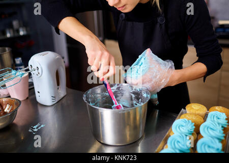 Le confiseur fait une crème pour les cupcakes sur une table de cuisine. Banque D'Images