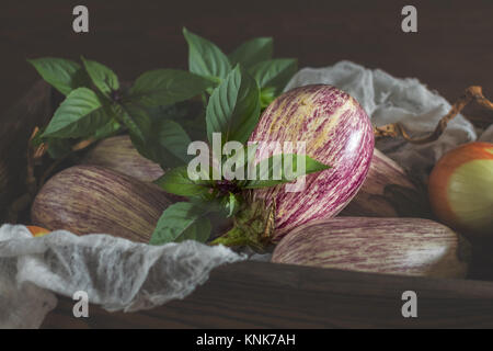 Graffiti violet aubergine, l'oignon vert et le basilic frais dans une boîte en bois dans un fond de bois dans un style rustique, selective focus Banque D'Images