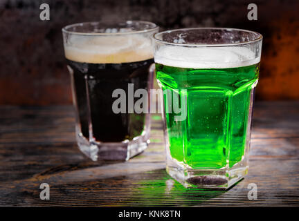 Deux grands verres avec dark fraîchement coulé et la bière verte sur un bureau en bois. Aliments et boissons concept Banque D'Images