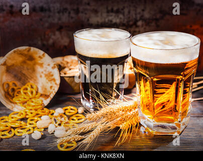 Deux grands verres avec dark et light fraîchement coulé près de la bière de blé, dispersés sur les bretzels petit bureau en bois foncé. Aliments et boissons concept Banque D'Images