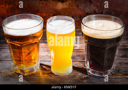 Trois verres de lumière, non filtré et bière brune sur un bureau en bois. Aliments et boissons concept Banque D'Images