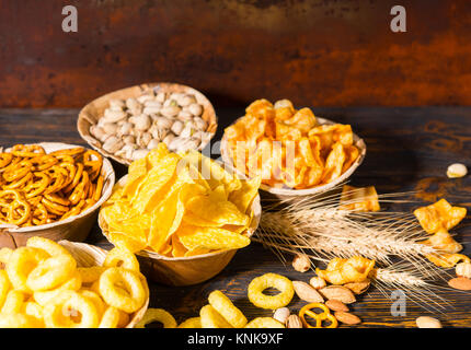 Les plaques en bois avec des collations près de blé, les noix et les bretzels éparpillés sur le bureau en bois sombre. Aliments et boissons concept Banque D'Images