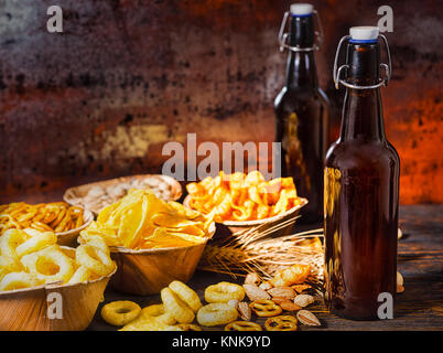 Les plaques en bois avec des collations près de deux bouteilles de bière, blé, noix et dispersés sur les bretzels en bois 24. Aliments et boissons concept Banque D'Images