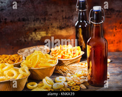 Les plaques avec des collations près de deux bouteilles de bière, blé, noix et dispersés sur les bretzels en bois 24. Aliments et boissons concept Banque D'Images