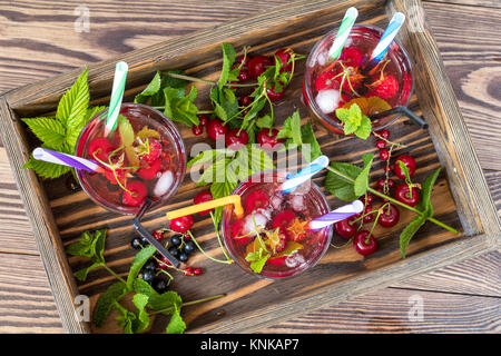 Trois verres de boisson rafraîchissante au parfum de fruits frais en boîte en bois entourée de fruits. Vue d'en haut. Fond de bois Banque D'Images