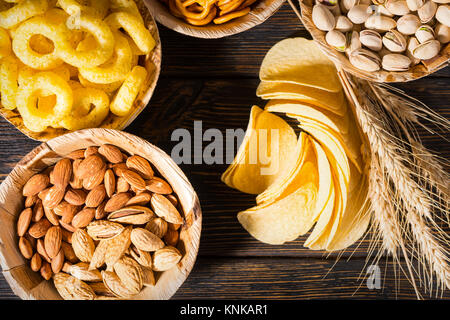 Vue de dessus des plaques avec les pistaches, noix et autres collations près de blé, copeaux éparpillés sur un bureau en bois sombre. Aliments et boissons concept Banque D'Images