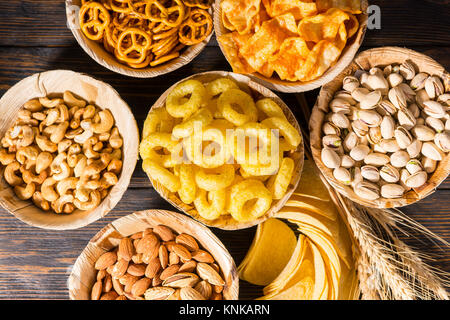 Vue de dessus des plaques avec les pistaches, noix et autres délicieuses collations près de la bière de blé, copeaux éparpillés sur un bureau en bois sombre. Aliments et boissons concept Banque D'Images