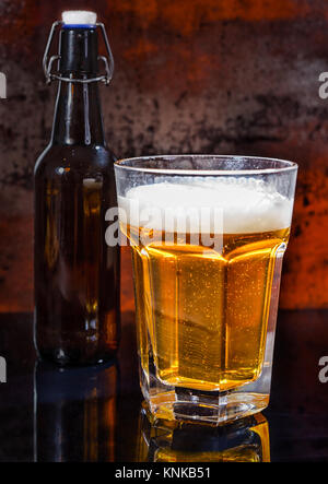 Plein verre de bière légère et la bière bouteille noire sur une surface de miroir. Aliments et boissons concept Banque D'Images