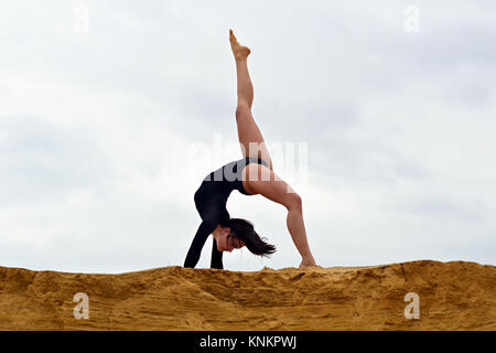 Pas de soutien de l'étirement des muscles des jambes avec une poignée (sur le fond de ciel nuageux) Banque D'Images