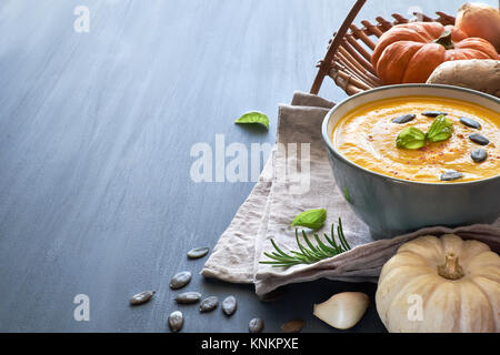 Soupe de potiron épicée au gingembre de Wit, l'oignon et l'ail, servi avec le basilic, les graines de citrouille et séché au piment. Fond de bois, de l'espace texte Banque D'Images