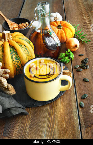 Soupe de potiron épicée au gingembre et l'oignon, servi dans une tasse avec de l'huile de citrouille et les croûtons sur la table en bois. Cette variation est l'allemand de la citrouille sou Banque D'Images