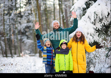 Portrait de famille dans la forêt d'hiver. Famille heureuse dans le contexte d'arbres couverts de neige. Banque D'Images