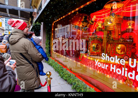 Les gens de la scène de Noël, père tenant bébé regardant Saks Fifth Avenue fenêtre de Noël dans le centre-ville de Toronto, Canada. Banque D'Images