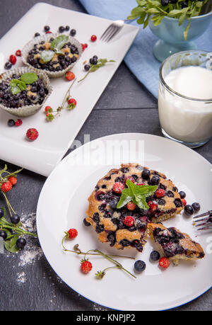 Muffin aux myrtilles et petits fruits fraises sur une assiette blanche et une table en bois servi avec du lait et de baies fraîches et Banque D'Images