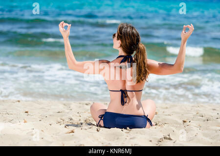 Frau im Bikini Joga macht am Strand, Spanien, Ibiza - femme ne le yoga à la plage, Ibiza, Espagne Banque D'Images