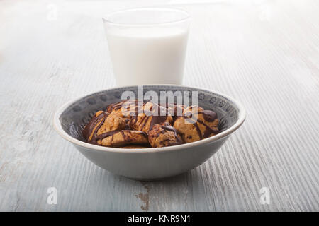 Les cookies à l'avoine dans un bol et verre de lait sur la table en bois. Banque D'Images