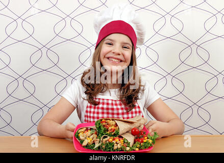 Happy little girl cook avec burritos sur la plaque Banque D'Images