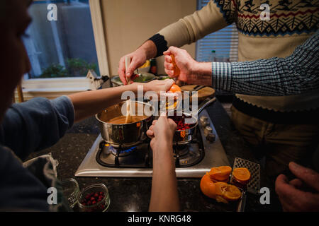 Petit garçon est d'aider son père et son grand-père faire un dîner de Noël. Le garçon est râper le zeste d'orange, le grand-père est Presser les oranges et le Banque D'Images