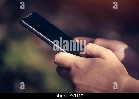 Pregnant woman texting outdoors on park bench, adulte femelle de race blanche à l'aide de téléphone mobile pendant la grossesse Banque D'Images