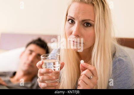 Worried woman prendre une pilule avant de dormir la nuit Banque D'Images