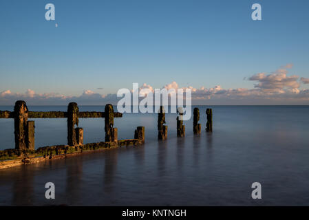 Vue paysage pittoresque pittoresque d'épis de défense contre la mer à Littlehampton, West Sussex, UK dans joli coucher du soleil la lumière avec une exposition longue, lissée mer calme Banque D'Images