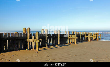 Vue d'une forte brise-lames en bois de la défense de la mer sur la plage de Walcott-sur-Mer, Norfolk, Angleterre, Royaume-Uni. Banque D'Images