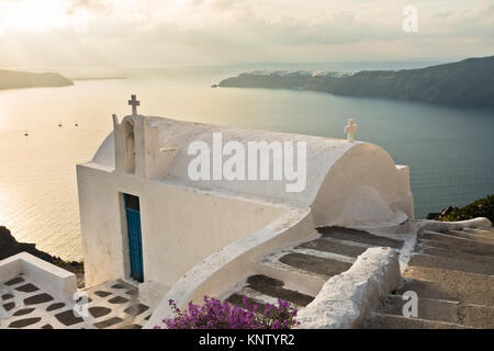 Petite église au coucher du soleil avec en arrière-plan le village d''Oia, Santorini Island Banque D'Images