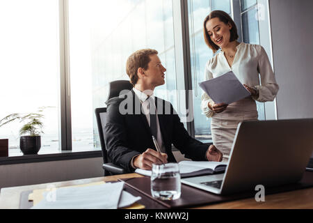 Deux hommes d'affaires travaillant ensemble au bureau. homme d'affaires assis à son bureau avec sa secrétaire lisant des notes dans un bureau moderne. Banque D'Images