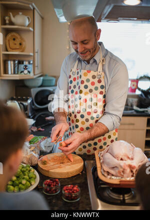 Père parle à son fils dans la cuisine alors qu'il se prépare un dîner de Noël. Le père est de l'épluchage des carottes. Banque D'Images