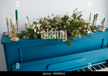 Gros plan du vieux piano peint bleu décoré de guirlande de noël et des bougies à la maison de célébration. Éléments de décoration de fête d'or. C horizontale Banque D'Images