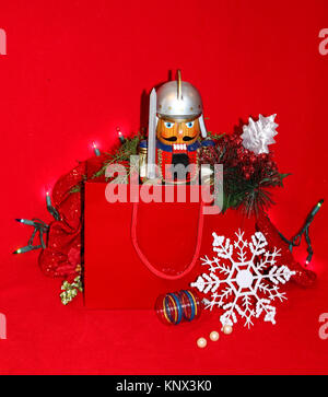 Soldat romain Casse-noisette présents dans un sac-cadeau sur fond rouge avec flocon, vintage ornament et Christms lights Banque D'Images
