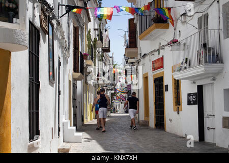 Trois jeunes hommes à pied dans gay street d'Ibiza en plein jour. Rue étroite et blanc, traditionnel bâtiments reflètent le style de vie de l'île et de la culture. C'est C Banque D'Images