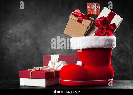 Santa's shoe avec coffrets cadeaux sur fond sombre Banque D'Images