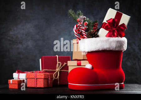 Santa's shoe avec coffrets cadeaux sur fond sombre Banque D'Images