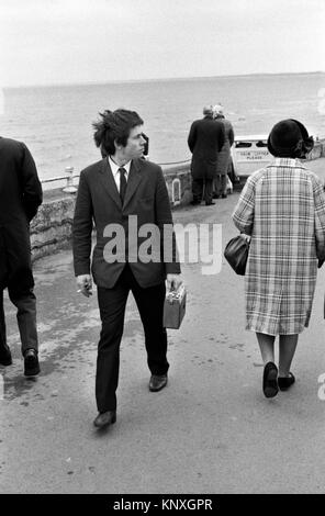 Adolescent marchant avec la radio à transistor rétro à l'ancienne la radio sans fil joue pendant qu'il marche le long de la promenade dans Bridlington Yorkshire 1972 1970s UK HOMER SYKES Banque D'Images