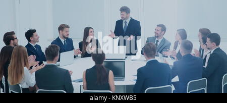 L'équipe commerciale d'encouragement et souriant Directeur commercial pour fermer la réunion d'affaires dans le bureau spacieux à la table ronde. Banque D'Images