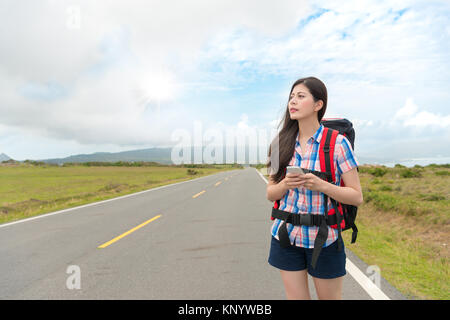 Attrayant élégant female hiker holding mobile smartphone marche sur route de campagne et à la suite de l'information en ligne Guide à destinati Banque D'Images