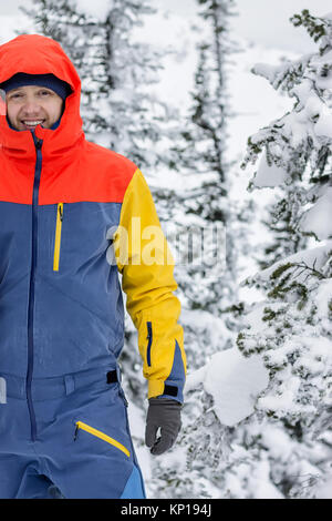 Freerider avec un snowboard dans des combinaisons se dresse au sommet d'une montagne enneigée. Banque D'Images