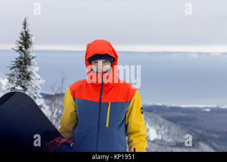 Freerider avec un snowboard dans des combinaisons se dresse au sommet d'une montagne enneigée. Banque D'Images