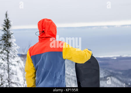 Freerider avec un snowboard dans des combinaisons se dresse au sommet d'une montagne enneigée. Banque D'Images