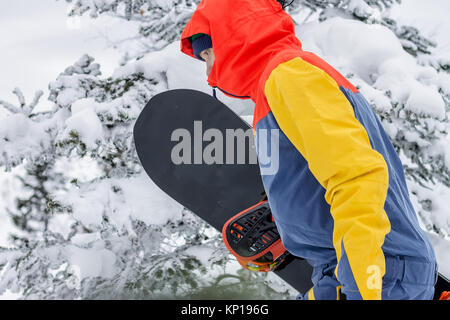 Freerider avec un snowboard dans des combinaisons se dresse au sommet d'une montagne enneigée. Banque D'Images