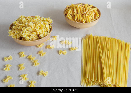 Composition des pâtes italiennes non cuits. Les pâtes dans une poterie. Spaghetti, farfalle, fusilli sur fond gris. Pâtes crues arrière-plan. Banque D'Images