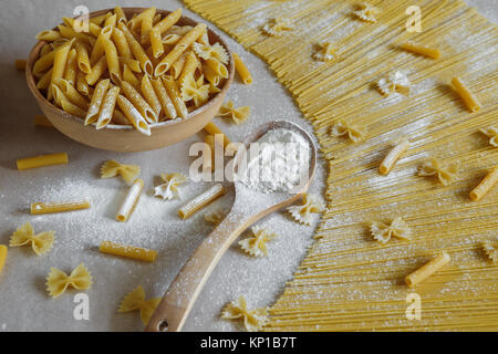 Composition des pâtes italiennes non cuits. Les pâtes dans une poterie. Spaghetti, farfalle, fusilli sur fond gris. Pâtes crues arrière-plan. Banque D'Images