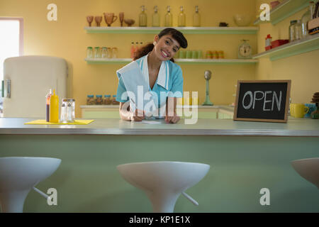 Portrait of waitress standing at counter in restaurant Banque D'Images
