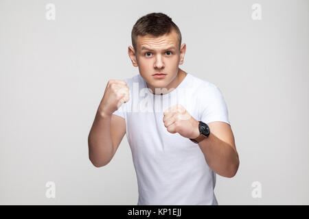 La boxe. Jeune homme colère, prêts à se battre. Mur Gris, Studio shot Banque D'Images