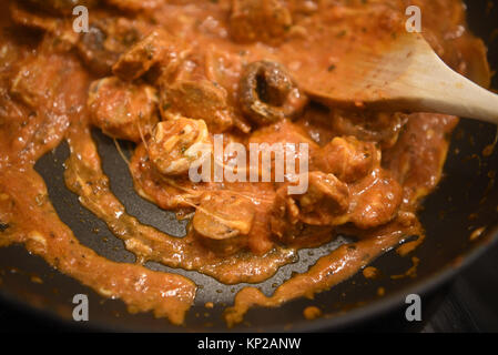 Fermer l'alimentation photographie image de la cuisson des aliments dans la poêle chaude avec des ingrédients de fines herbes oignon champignons tomate épices et fromage de fusion avec une cuillère en bois Banque D'Images